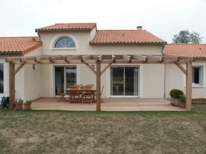 Pergola extérieure en bois adossée à une maison réalisée par Pasquereau